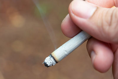Close-up of hand holding cigarette