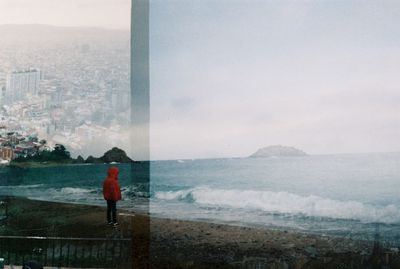 Rear view of man standing by sea against sky