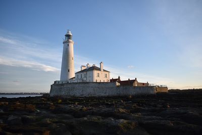 Lighthouse amidst buildings against sky