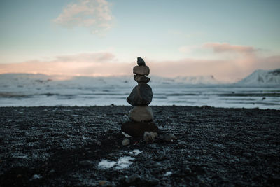 Rocks stacked at beach against sky during sunset