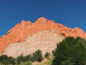 Low angle view of rock formations against clear blue sky