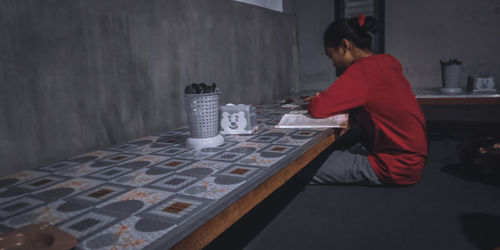 Side view of woman sitting on table