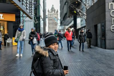 Portrait of boy in warm clothing standing on city street