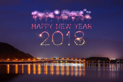 Illuminated firework display over river at night