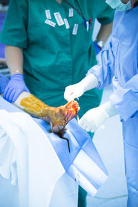 Midsection of surgeons operating patient at hospital