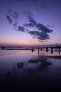 Scenic view of beach against sky at sunset