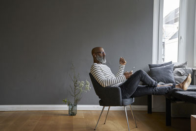 Mature man sitting with feet up, using smartphone
