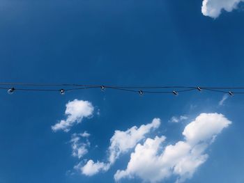 Low angle view of light bulbs against blue sky