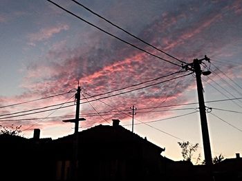 Low angle view of electricity pylon against cloudy sky