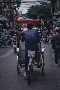 Rear view of man riding bicycle on street