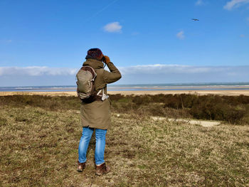 Full length rear view of woman viewing over sea