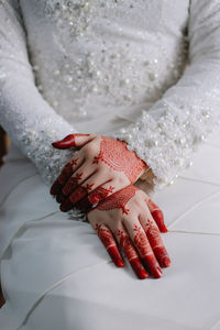 Midsection of bride with henna tattoo during wedding ceremony