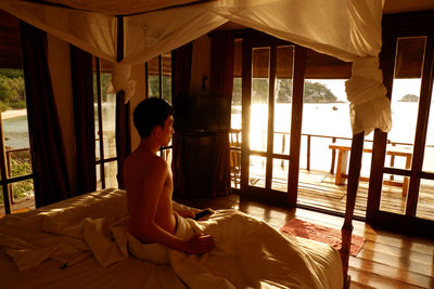 Woman sitting on bed at home