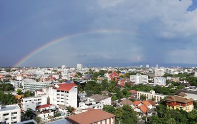 Rainbow over buildings in city against sky