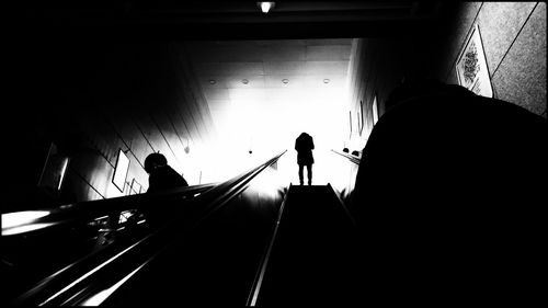 Silhouette people on escalator in building