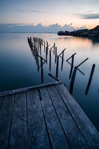 Wooden jetty in lake against sky during sunset