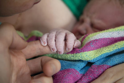 Cropped hand of newborn baby holding finger