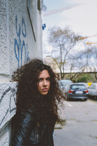 Portrait of young woman leaning on wall