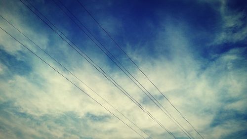 Low angle view of electricity pylon against blue sky