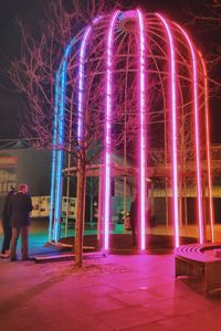 Rear view of man standing against illuminated lights at night