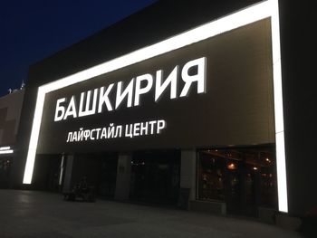 Low angle view of illuminated sign against clear sky at night