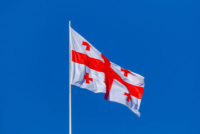 Low angle view of flag on pole against clear blue sky