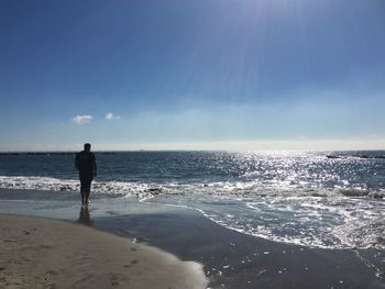 Rear view full length of man standing at beach against sky