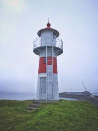 Lighthouse on field against sky