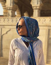 Woman wearing scarf while standing against historic building