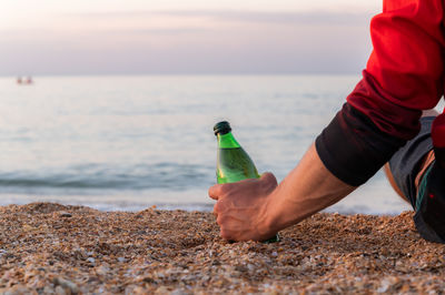Cropped hand of man holding sand at beach