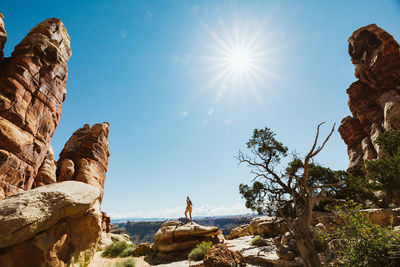 Man standing on rock formation against sky