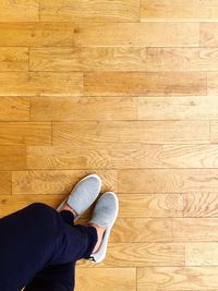 Low section of man standing on hardwood floor