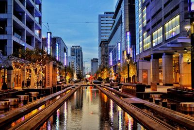 Canal amidst buildings in city at dusk