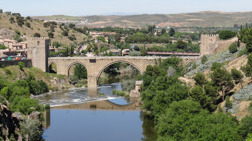 Arch bridge over river against sky