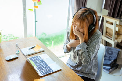 Rear view of girl sitting on table at home