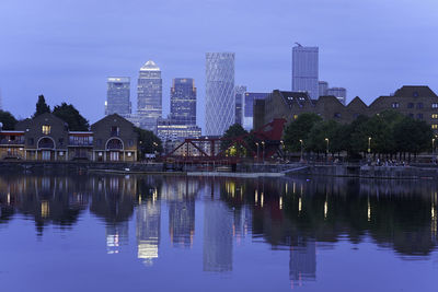 Reflection of buildings in lake against blue sky