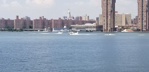 Sea by buildings against sky in city