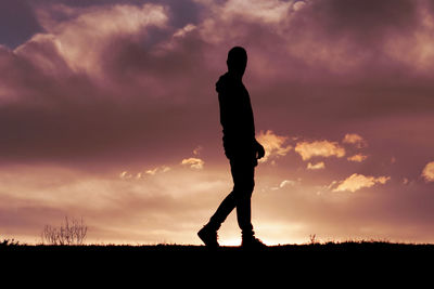 Silhouette woman standing on field against sky during sunset