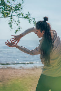 Woman standing at beach against sky