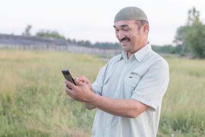 Mid adult man using mobile phone on field