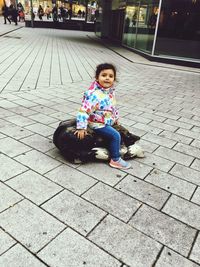 Full length of woman sitting on footpath