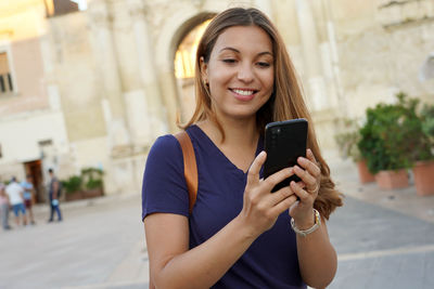 Dynamic stylish lady using satisfied her smartphone walking in the city. dutch angle.