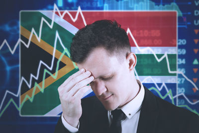 Close-up of stressed businessman touching forehead against flag