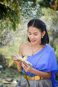 Smiling young woman holding lotus flower