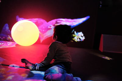 Boy playing with balloon in illuminated room
