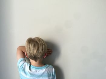 Rear view of boy standing by wall