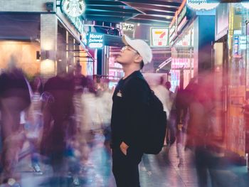 Side view of young woman in illuminated city at night