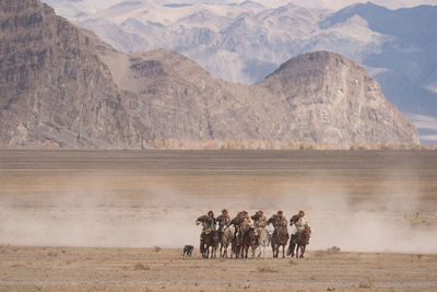 People in desert against mountains