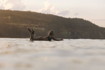 Female surfer in the ocean at sunset