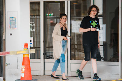 Full length of friends standing against wall